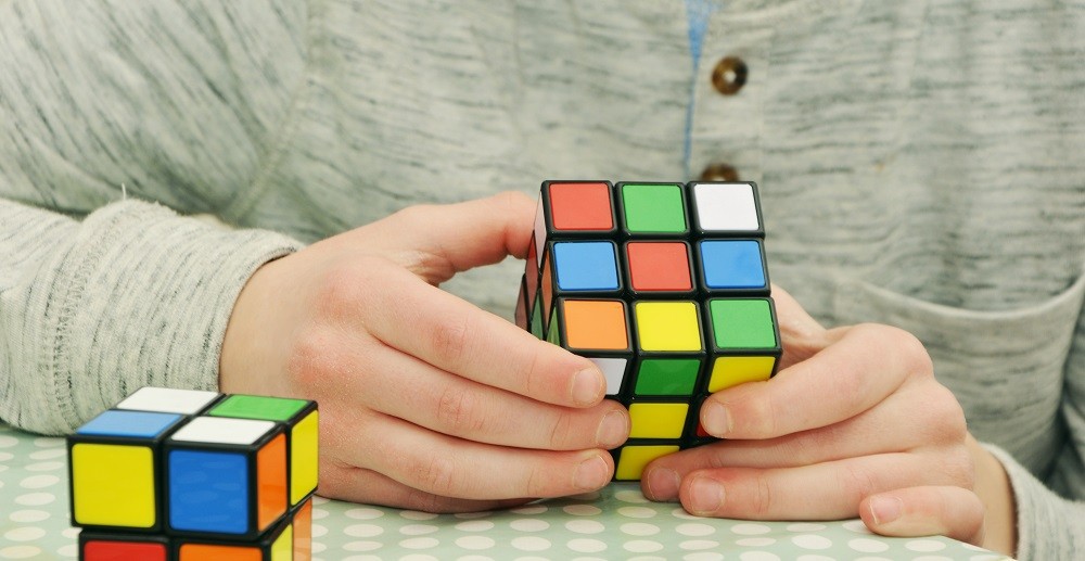 Someone is trying to solve a Rubiks cube. The colours are all mixed up