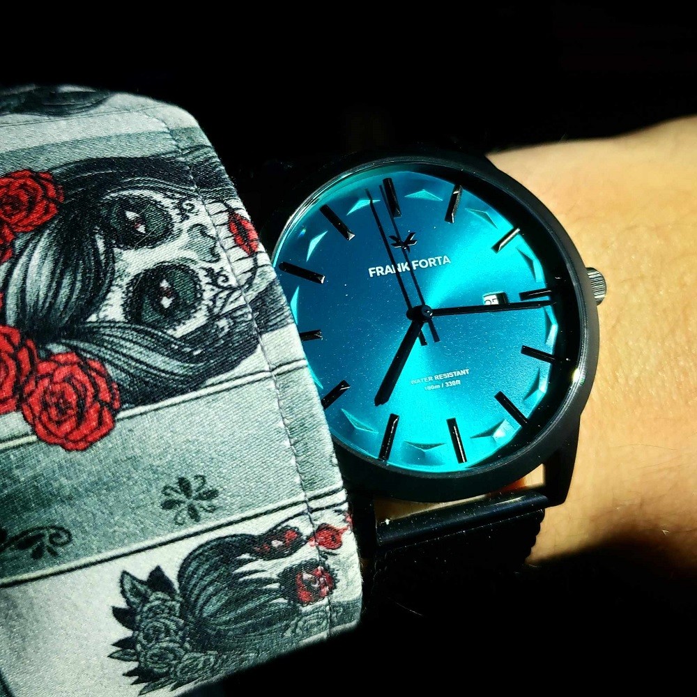 A vibrant blue watch with a black case is on a wrist. The blue dial is very close to the shade of deep blue you would find at Moraine Lake in Alberta, Canada