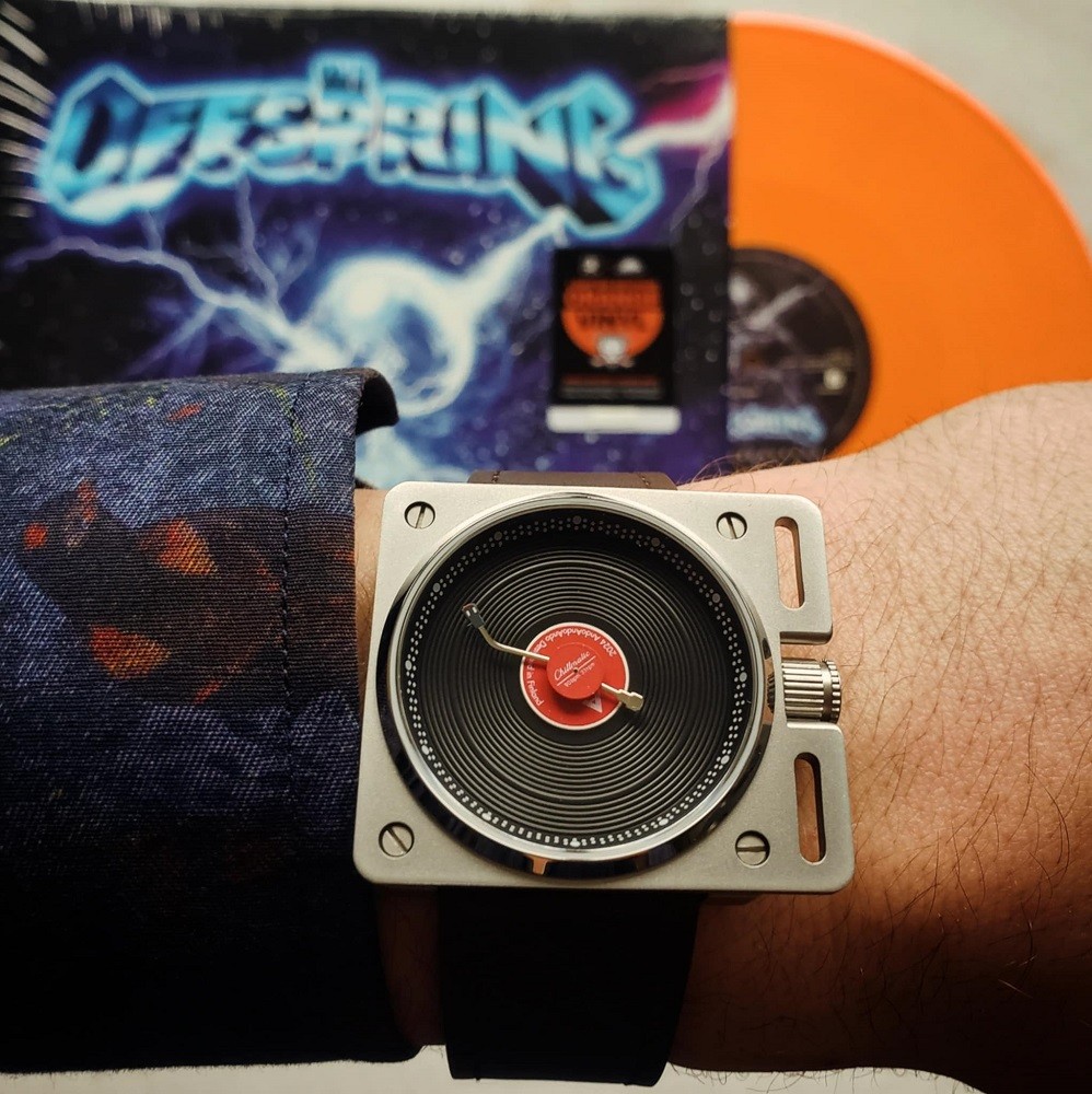 The Vinyl Record Watch by AndoAndoAndo features a unique dial in the shape of a vinyl record. The case is a large silver square similar to a turntable