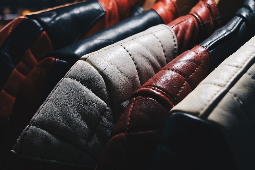 Several jackets are hung up on a rack at a coat check