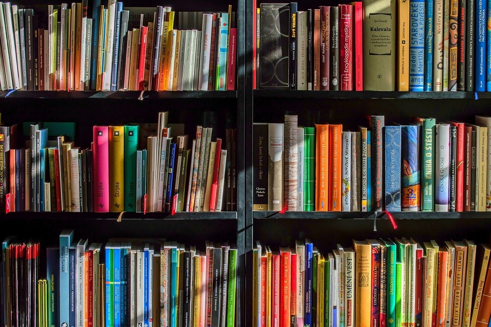 A shelf full of colourful books of all different shapes and sizes