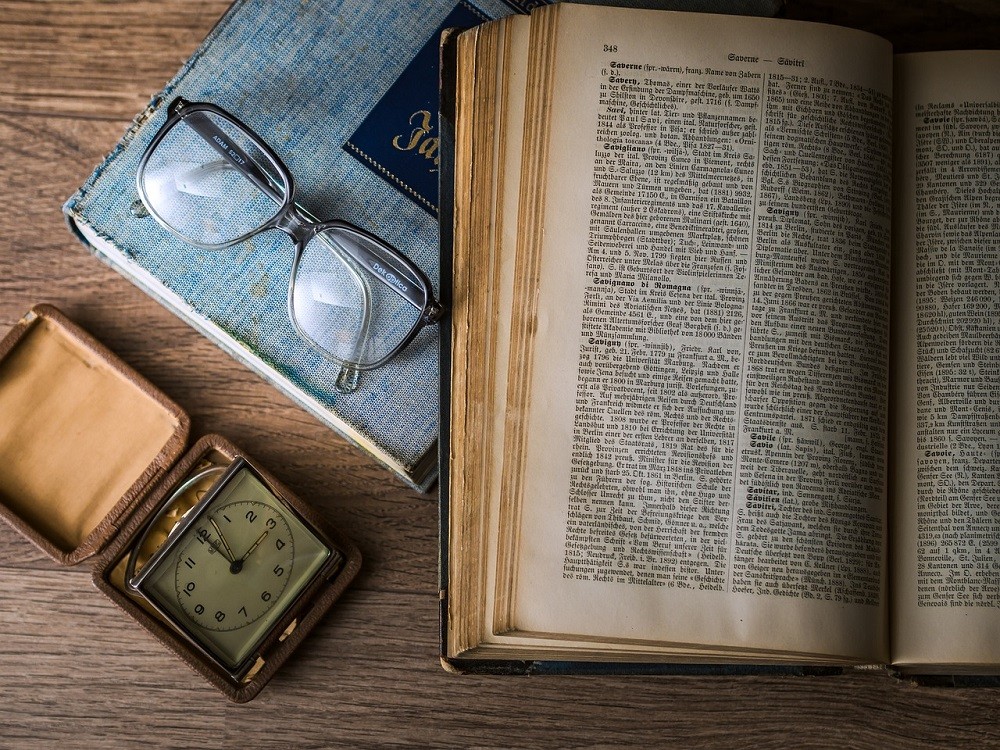 Effective reading begins with understanding what you are reading. An open book sits on a desk with a pair of reading glasses and vintage watch sitting beside it