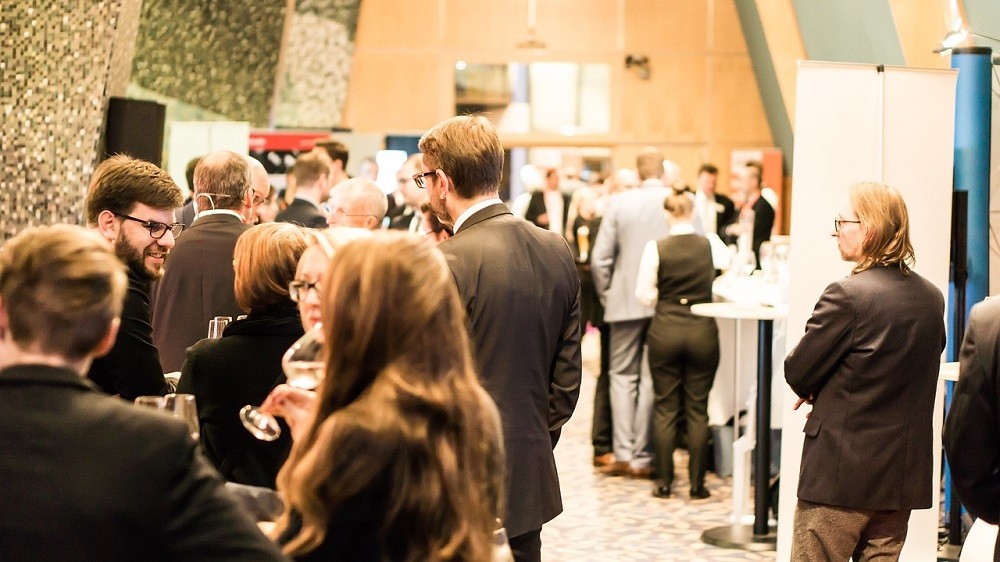 A large crowd of people are gathered at a conference. They are in business attire