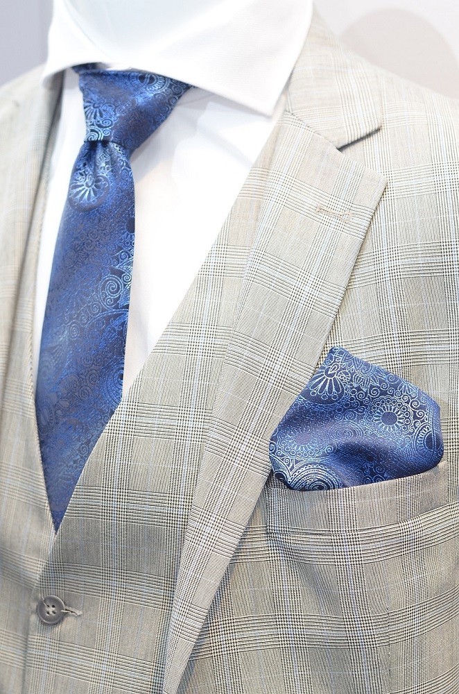 A man is wearing a white dress shirt and light grey sport coat. He has a matching blue tie and pocket square, a style sin that should be avoided at all costs