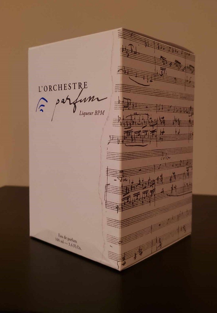 The front and side of Liqueur BPM is shown. The front displays the name of the cologne brand and name of the fragrance while the side is completely covered in piano sheet music