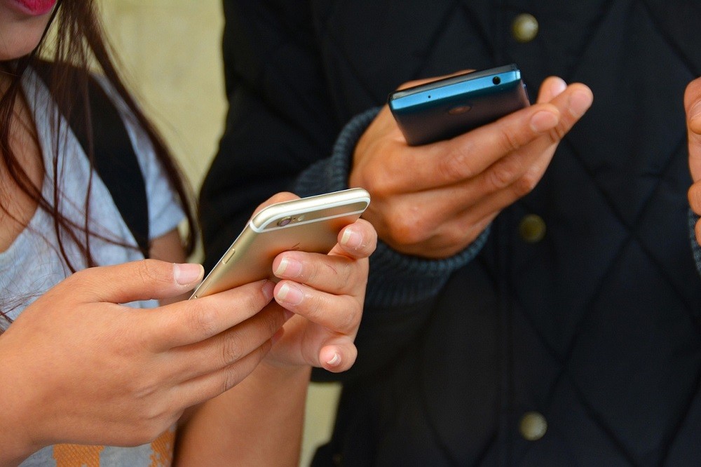 A man and woman look at their smartphones