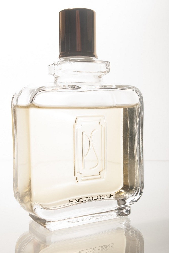 A bottle of cologne sits on a counter. It is almost completely full