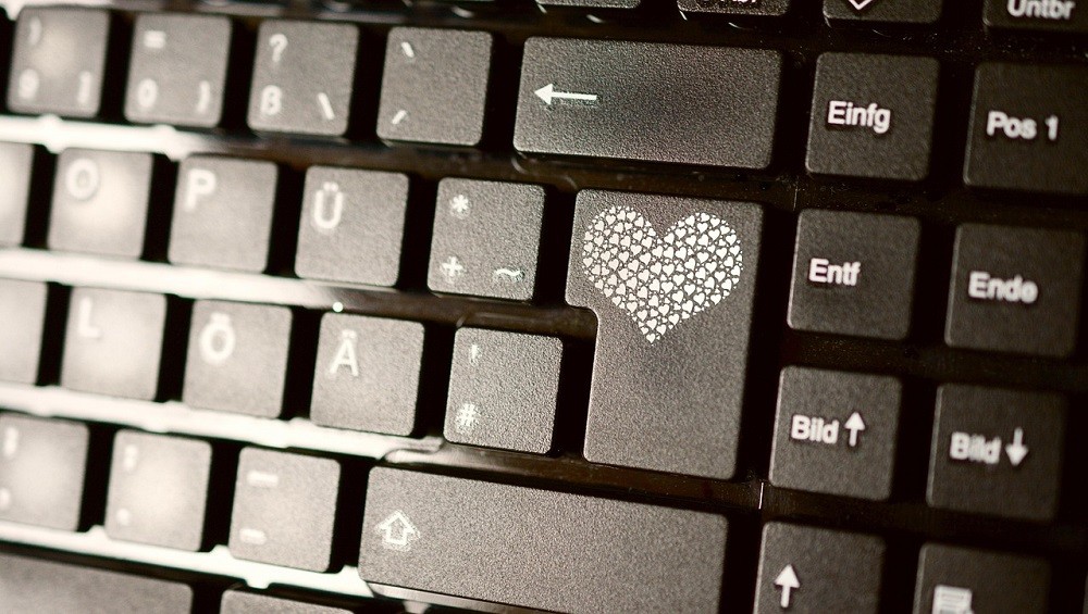 A black keyboard has a heart printed on the enter key