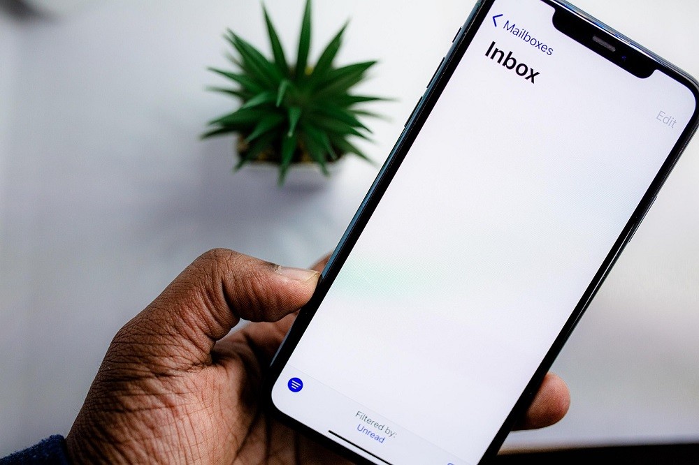 A man holds a smartphone. On the screen of the phone is his inbox. It is empty