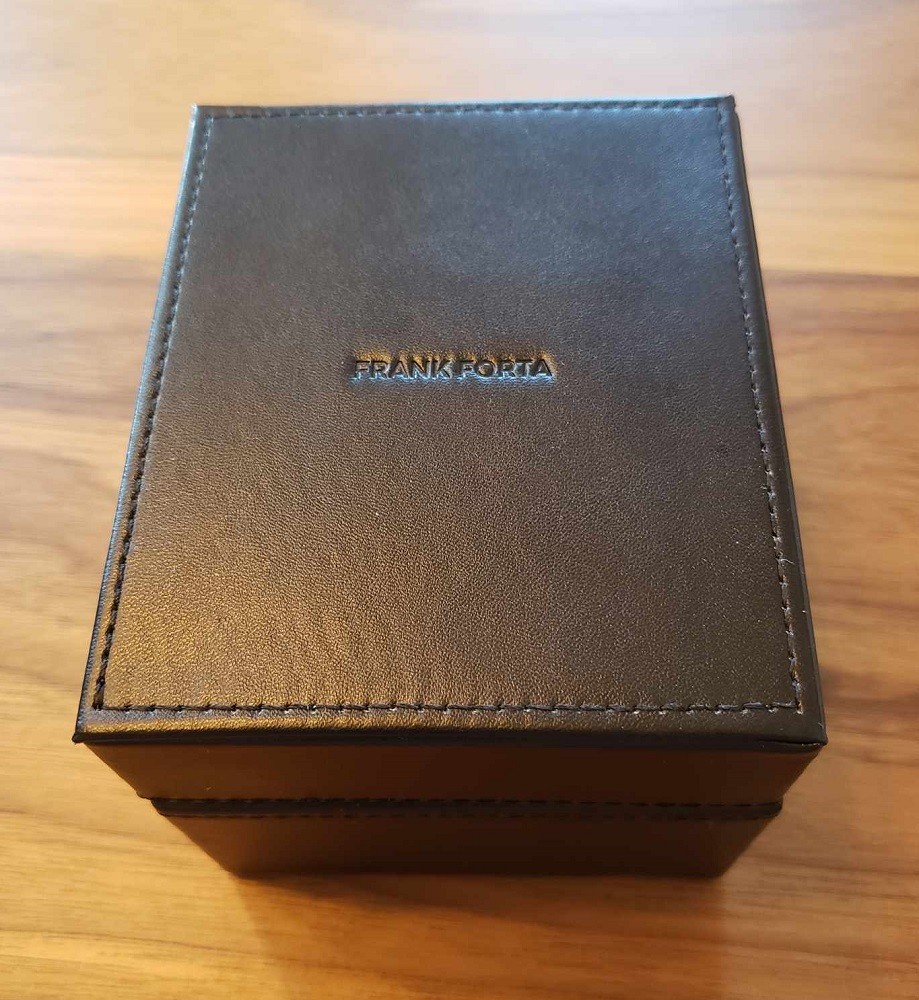 A Frank Forta watch box. It is a rectangular box made with black leather and features decorative stitching around the top of the box