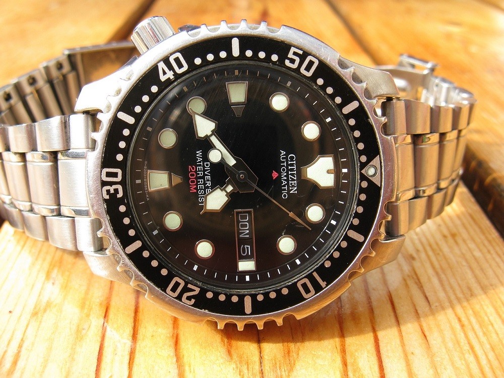 A black dial Citizen watch features a screw-down crown and shows the water resistance on the dial