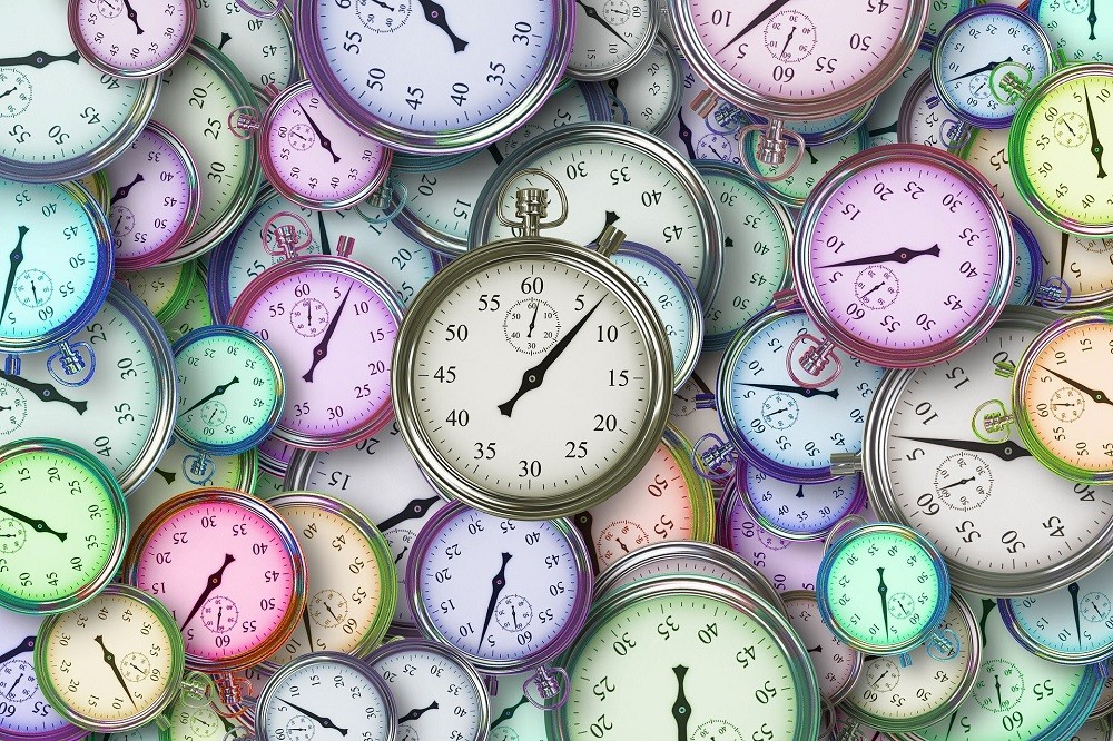 Dozens of neon coloured pocket watches and stop watches are piled up on top of each other all showing different time intervals