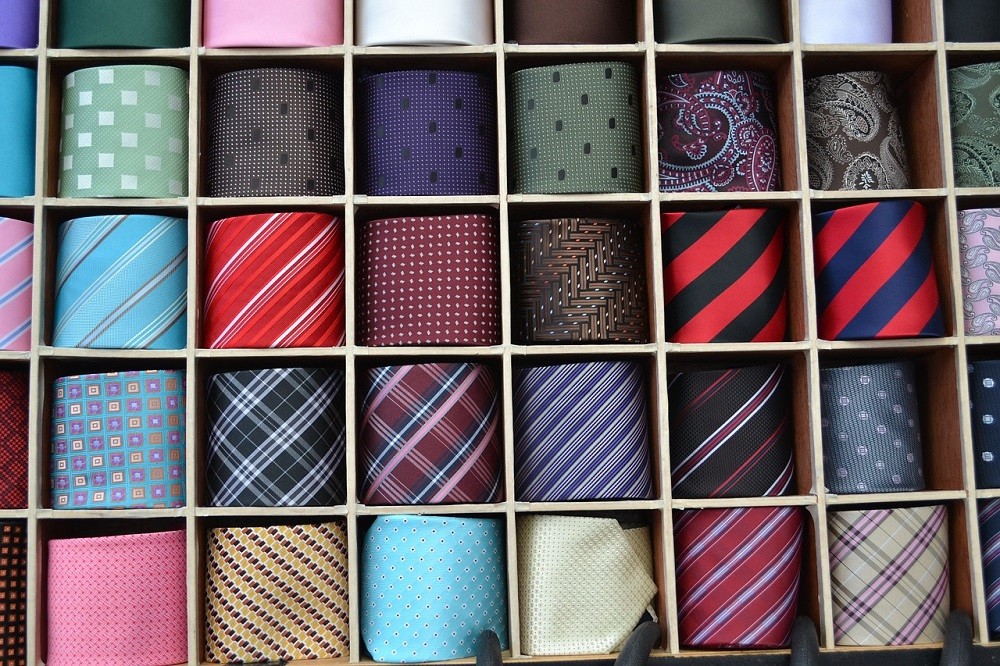 A tie organizer shows various ties rolled up and organized into the box. Each tie is separated by slots of wood