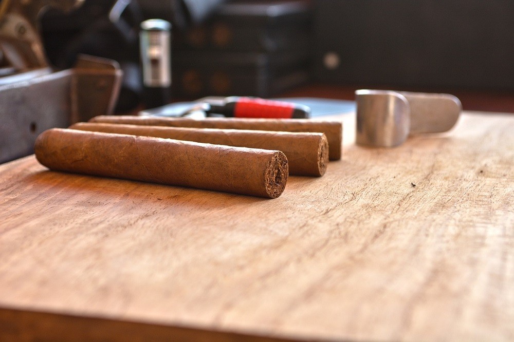 Three just-rolled cigars are on a wooden table