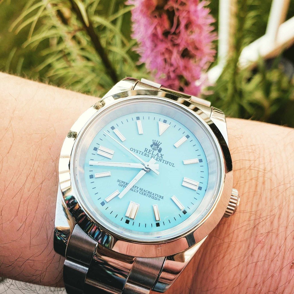 A knock-off teal Rolex watch has a silver case and stainless steel strap