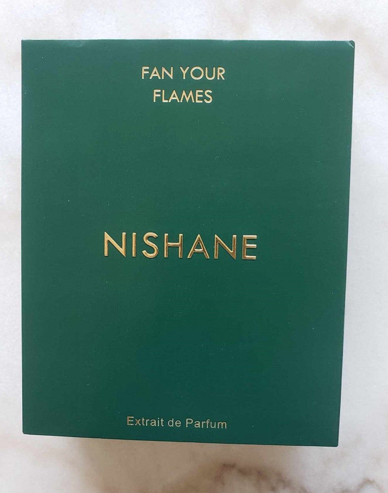 The box for Nishane Fan Your Flames is dark green. It is rectangular with gold lettering on it