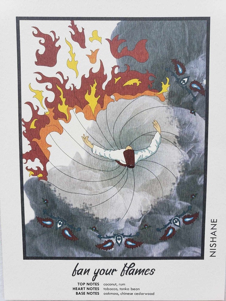 A postcard included with Fan Your Flames is a top-down view of a woman wearing a white dress. She is spinning. The dress is flared out and half of it is on fire