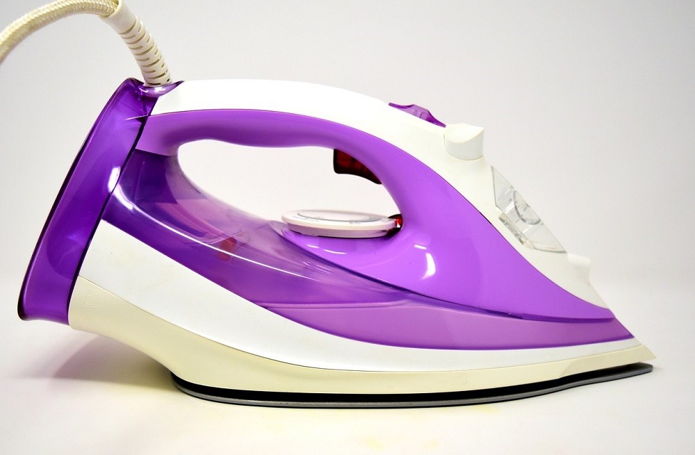 A purple and white iron lays with the element side down