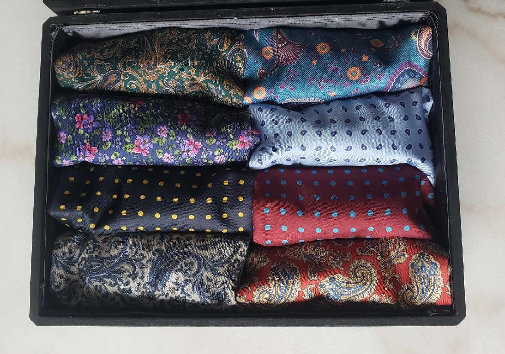 8 ascots rolled neatly into a wooden box for storage