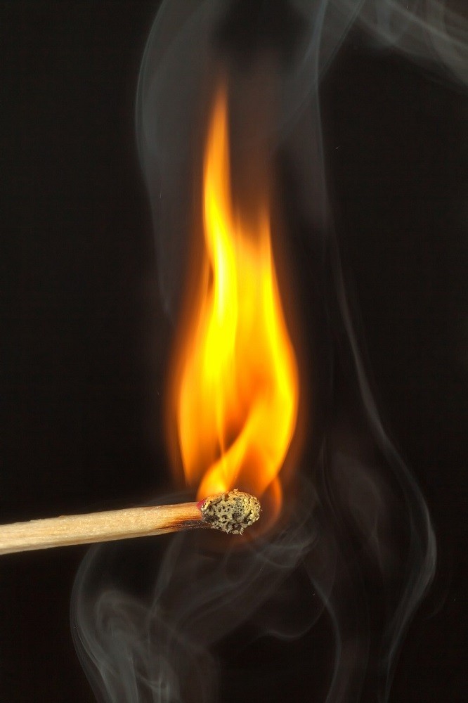 A lit match stick with the head engulfed in flames