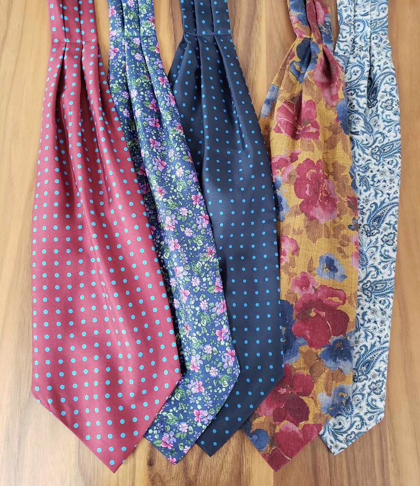 Cravats with different patterns and styles are laid out on a table