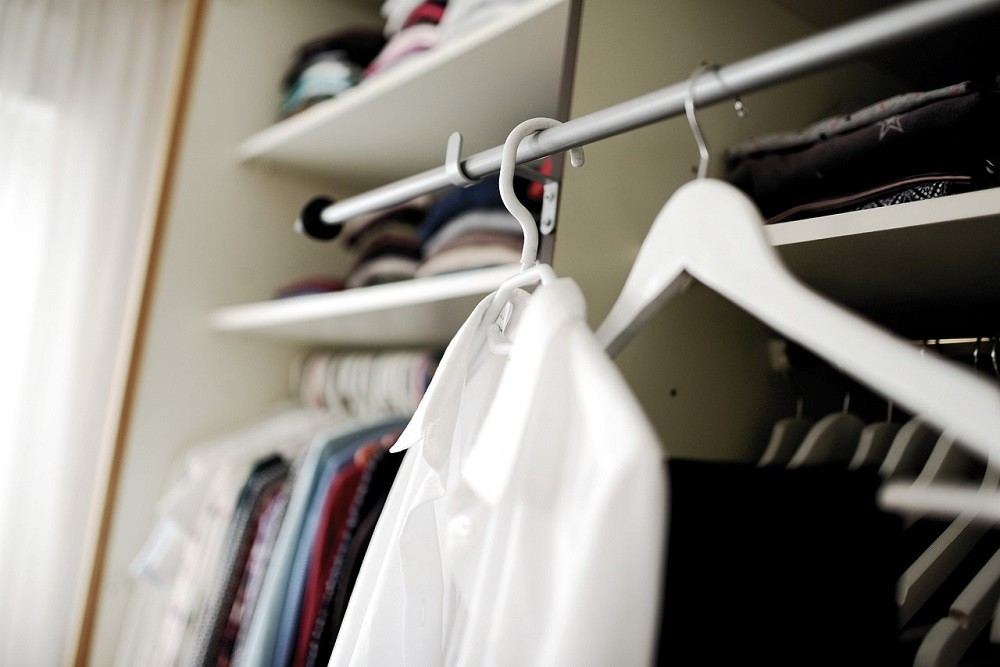 A white shirt hangs on a hangar in a closet