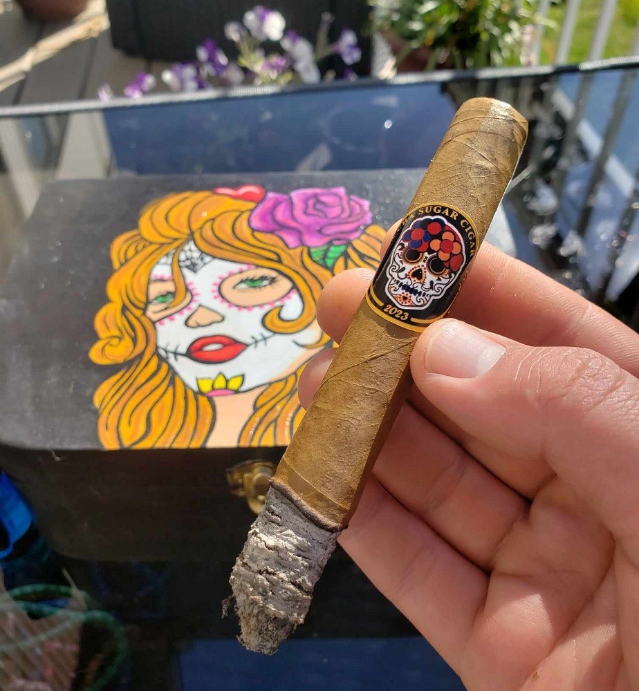 The first third of the Cha Cha Sugar cigar shows an inch of ash on the lit end. The cigar is light brown in colour