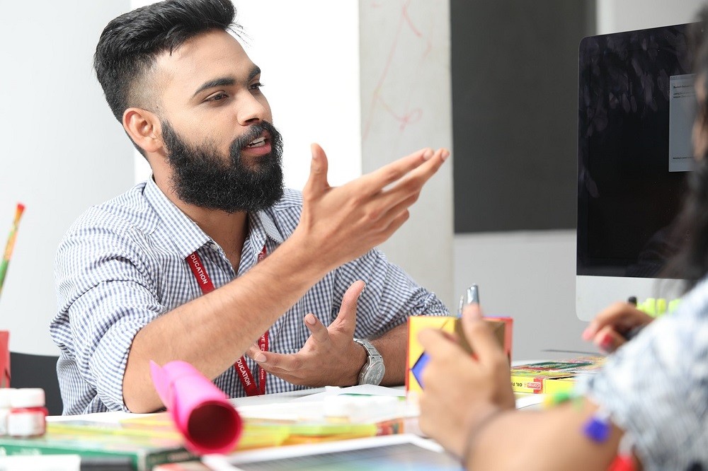 A middle aged man has his hands up. He appears to be arguing with someone out of frame