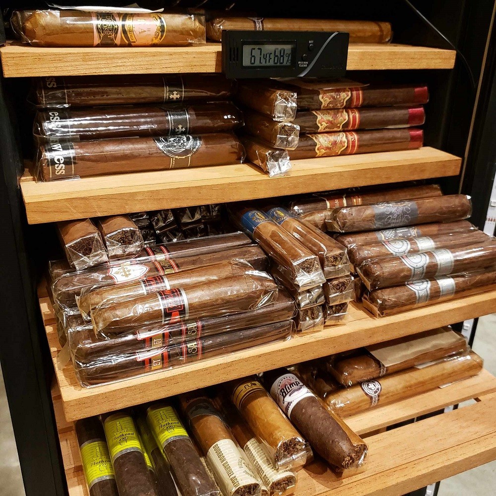 A wineador with multiple shelves containing many cigars of different shapes and sizes