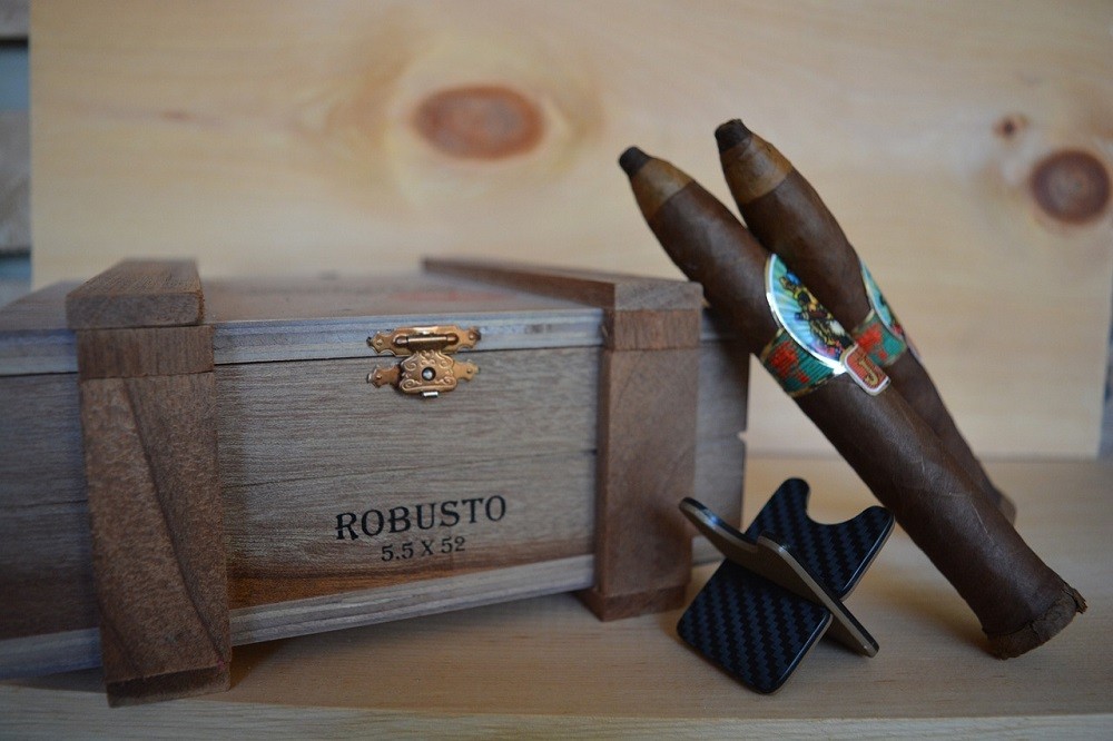 Two Osar Valldares Island Jim cigars are tiled against the box they came in