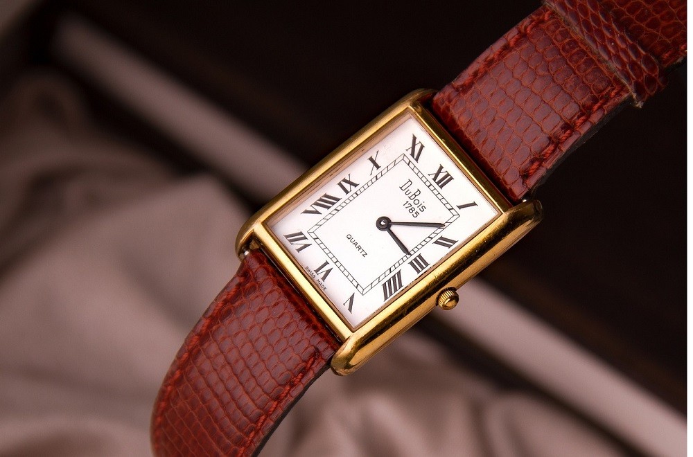 A generic rectangular quartz watch with a white face and gold case