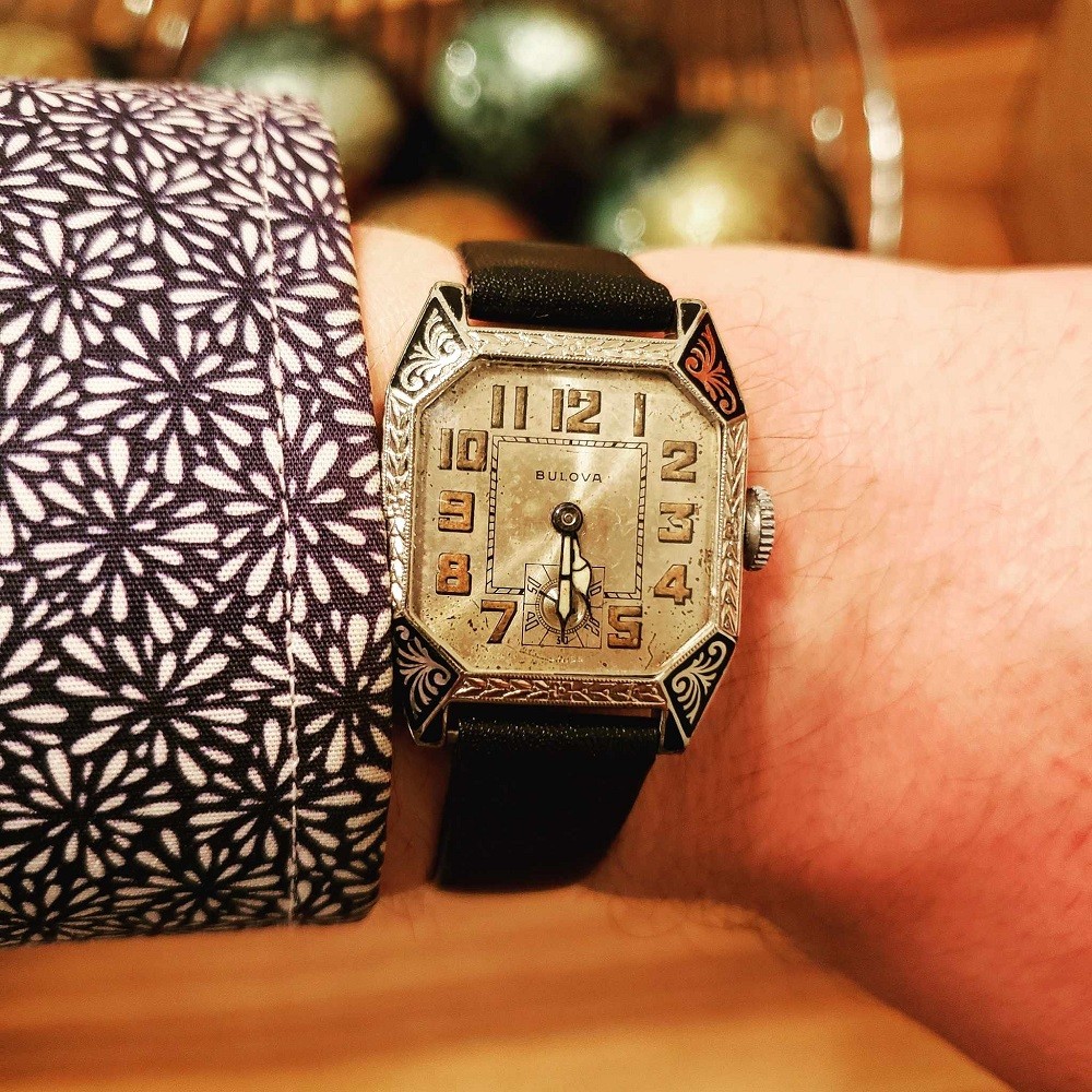 A vintage 1926 Bulova Conqueror with a silver face and a silver/black case with decorative engravings