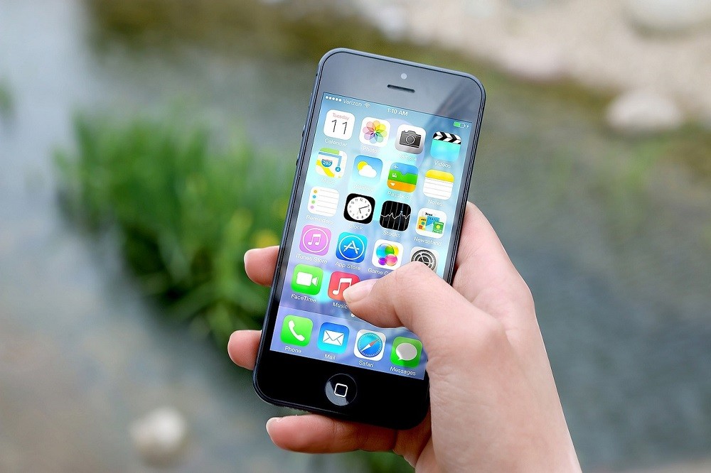 A simple picture of someone holding their smartphone. The homescreen shows a variety of apps ranging from social media to email to tools such as clock, settings, and camera