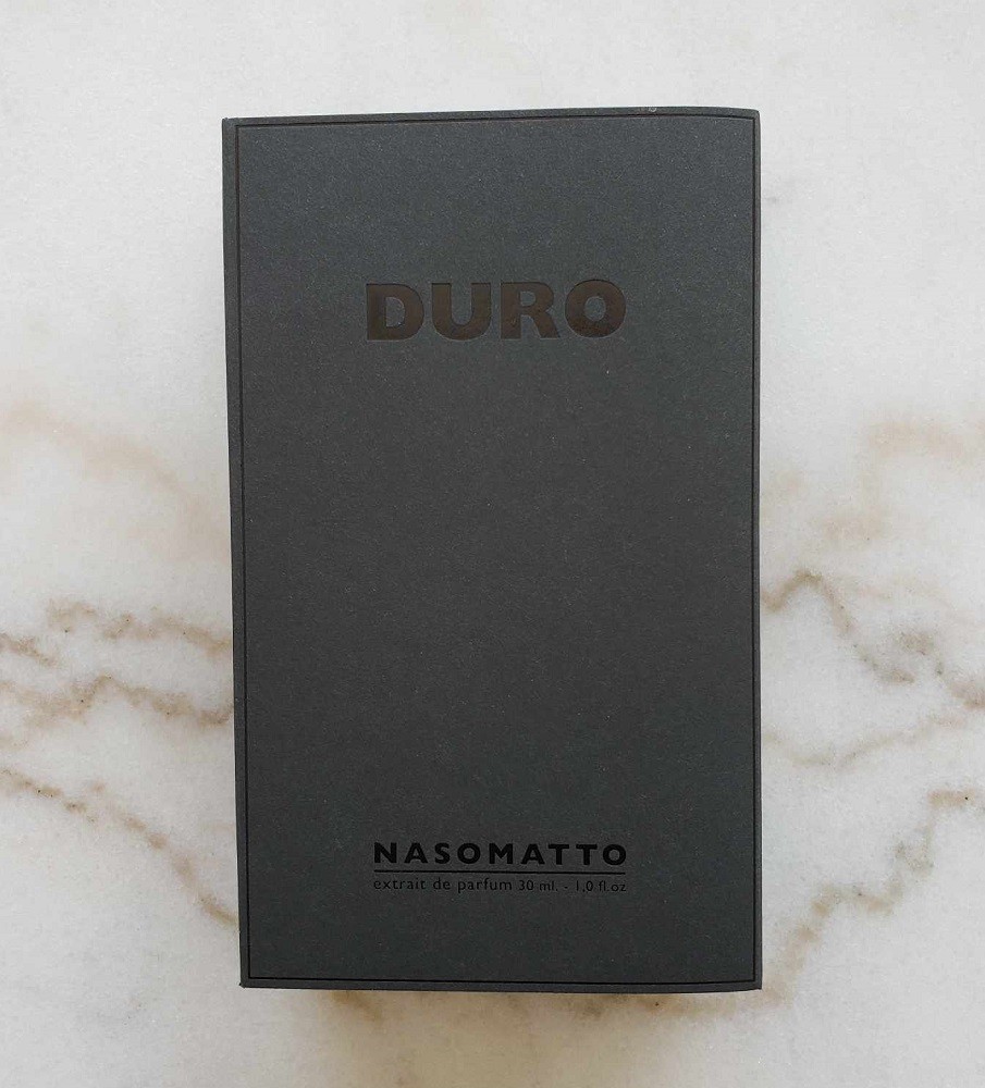 The box for Duro cologne by Nasomatto. It is matte black with shiny black lettering on it. The lettering is the name of the cologne on the top and the name of the brand on the bottom