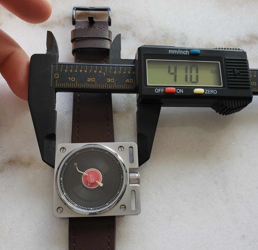 The width of the Vinyl Record Watch by AndoAndoAndo is 41mm. A caliper verifies this measurement with a digital display
