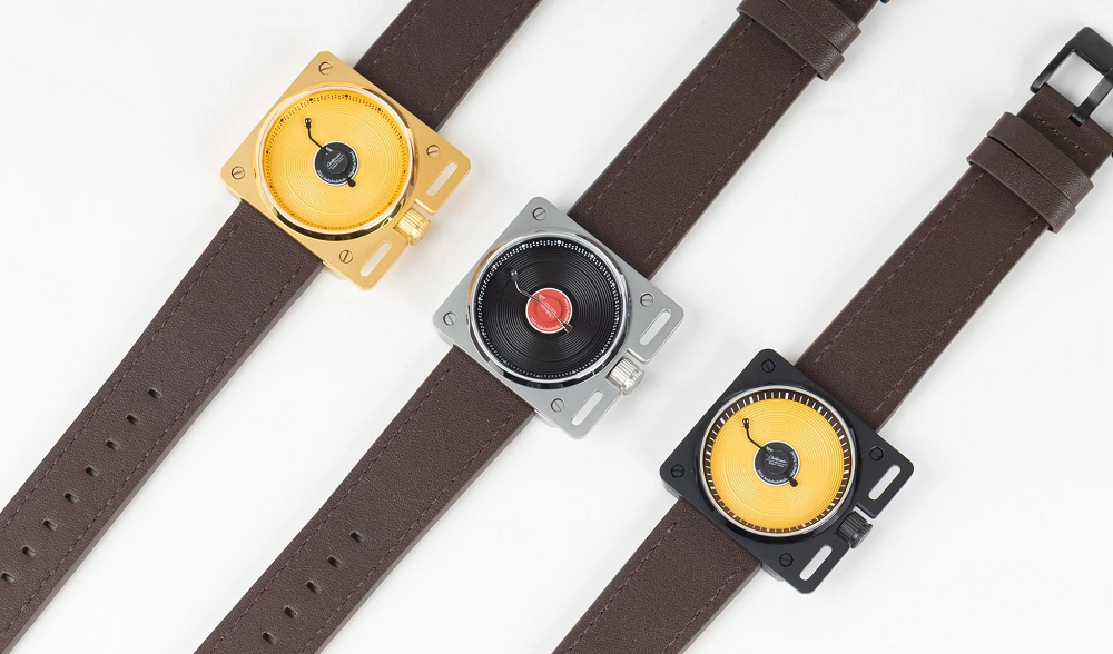 Three variations of the Vinyl Record Watch by AndoAndoAndo. One has a gold case and gold dial, one has a silver case with black dial, and one has a black case with gold dial. All three have brown leather straps