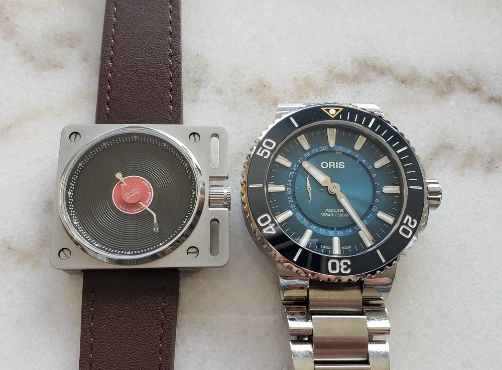 The Vinyl Record Watch by AndoAndoAndo beside an Oris Great Barrier Reef watch showing the same time