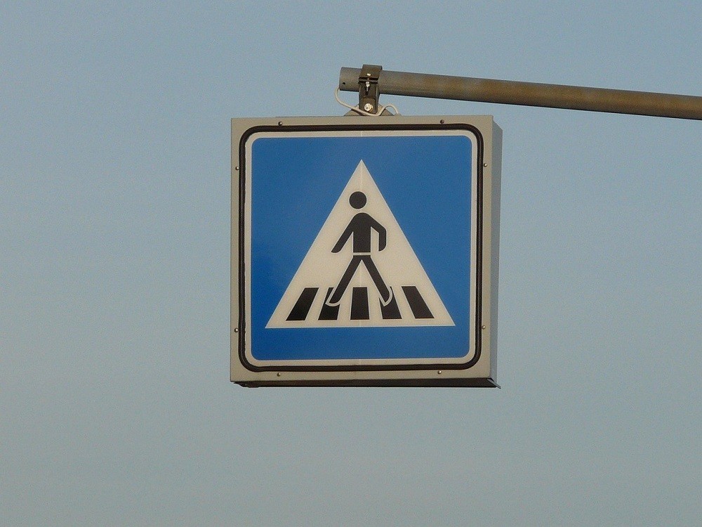 A traffic sign picturing a man crossing a sidewalk. This is likely a warning sign for drivers to slow down and pay attention to an upcoming crosswalk or intersection