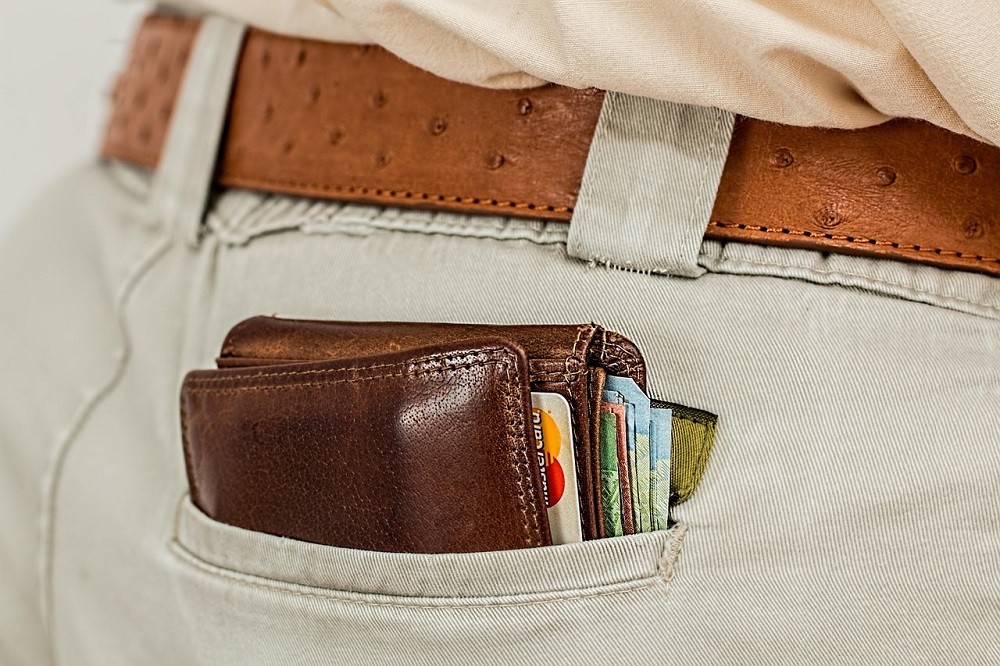 A brown wallet is dangerously close of falling out of someones back pocket. It could work its way out with each step the person takes