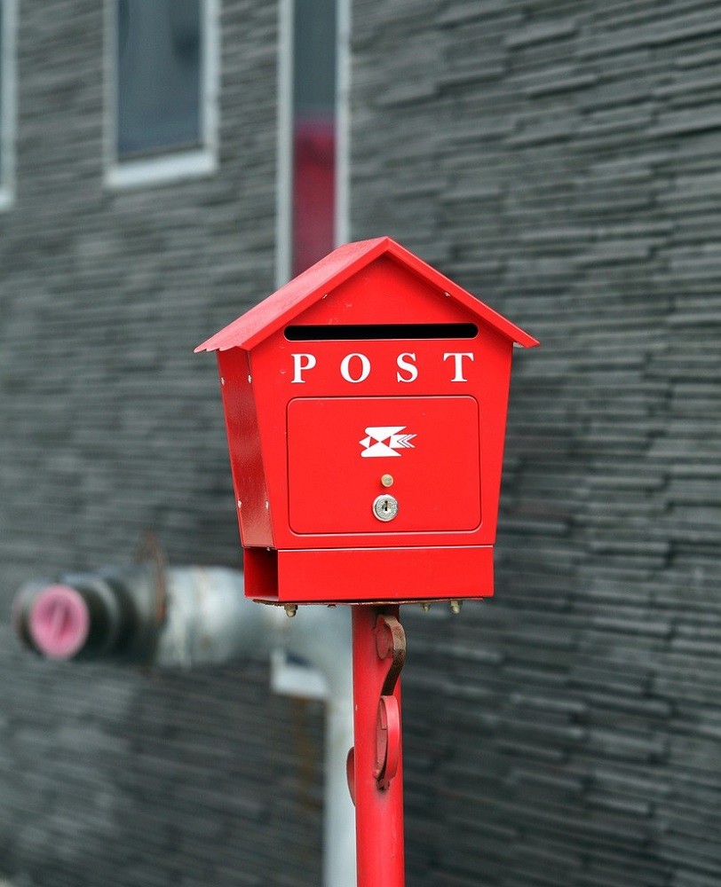 A bright red post box sits against a brick building