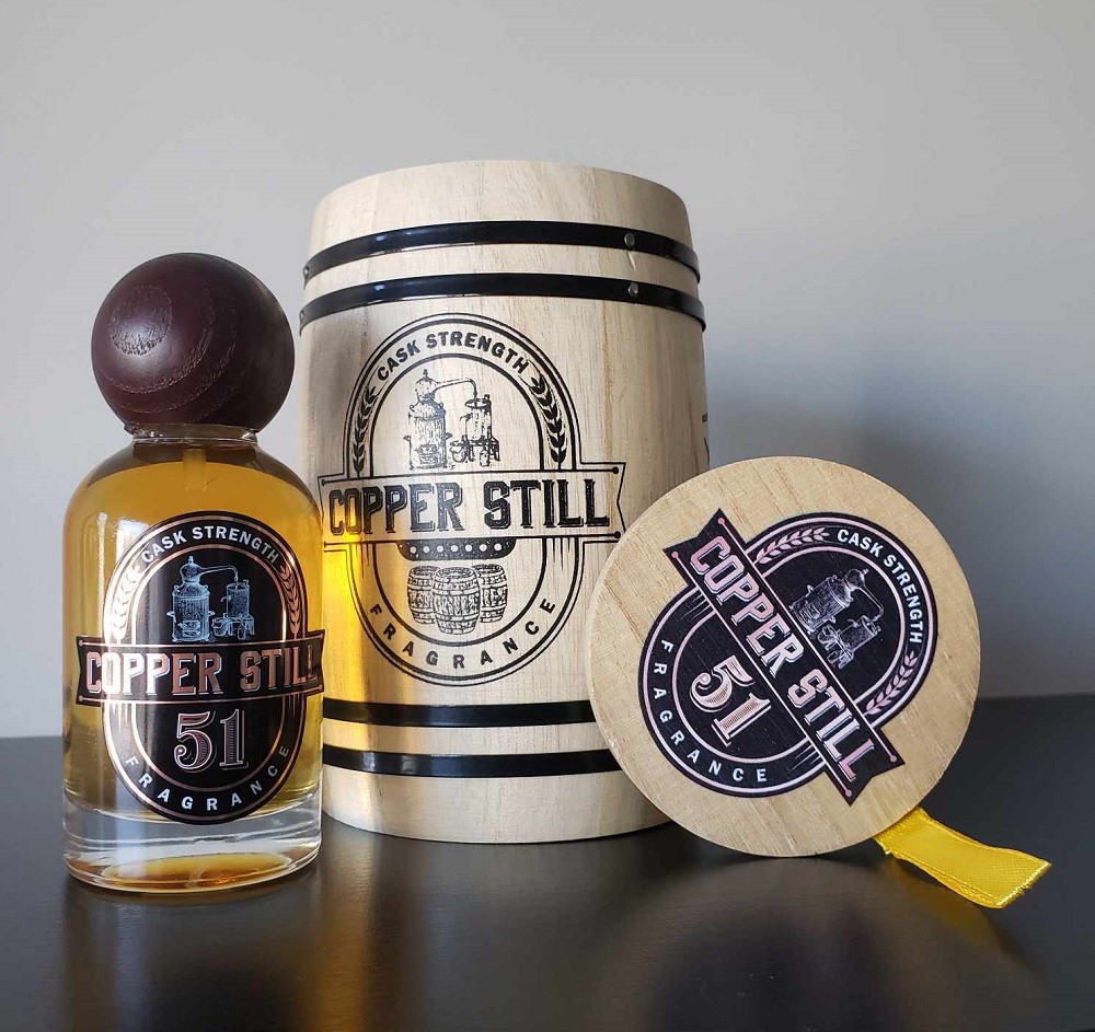 The bottle of 51 by Copper Still Fragrance is displayed with the miniature wooden whiskey barrel it is packaged in