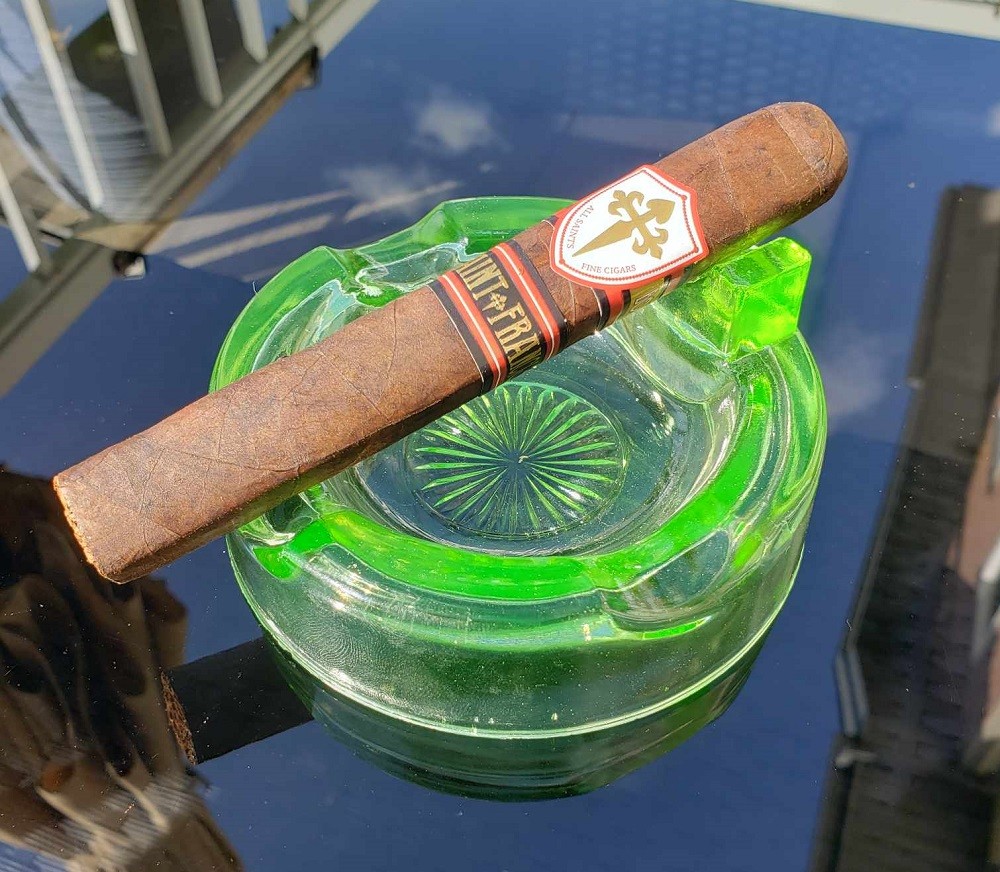 A cigar sits inside a green ashtray. The ashtray is made out of uranium glass, a popular type of glass during the 1930s to 1950s
