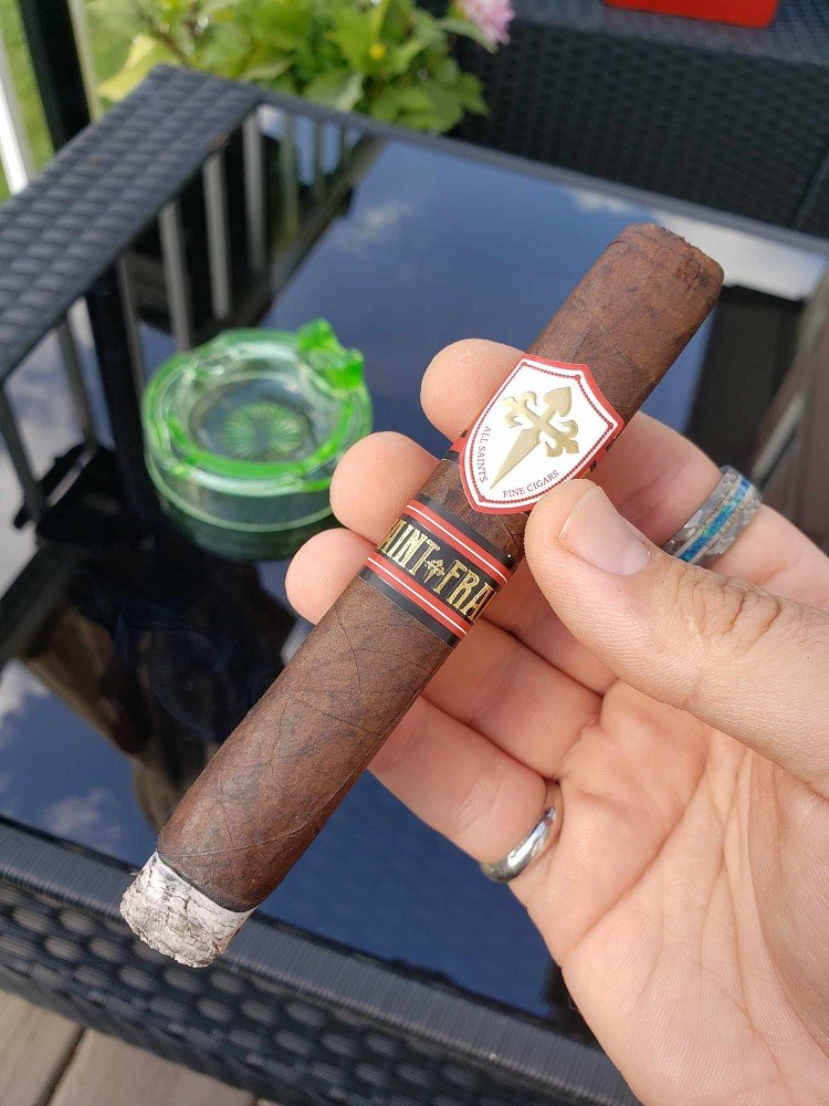 The Saint Francis All Saints cigar is lit and holds about half an inch of ash on the end