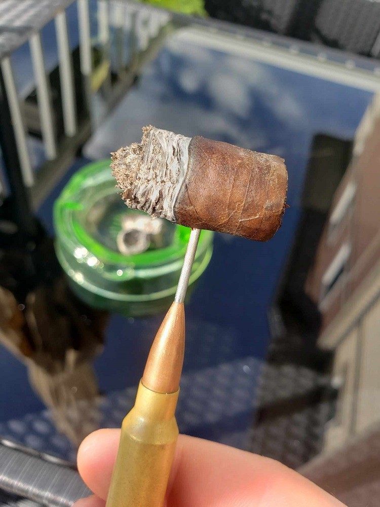 A cigar is smoked right down to the nub. There is less than half an inch left on it. It is being held by a nubber