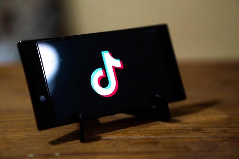A phone sits on a phone stand with the TikTok logo displayed