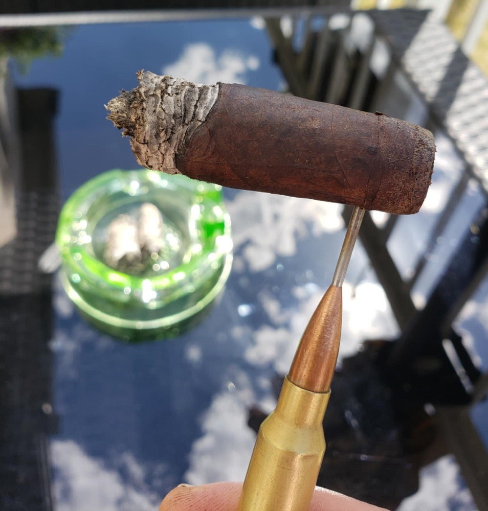 The La Historia cigar is chocolatey brown. The bands have been removed. The cigar is being held by a 