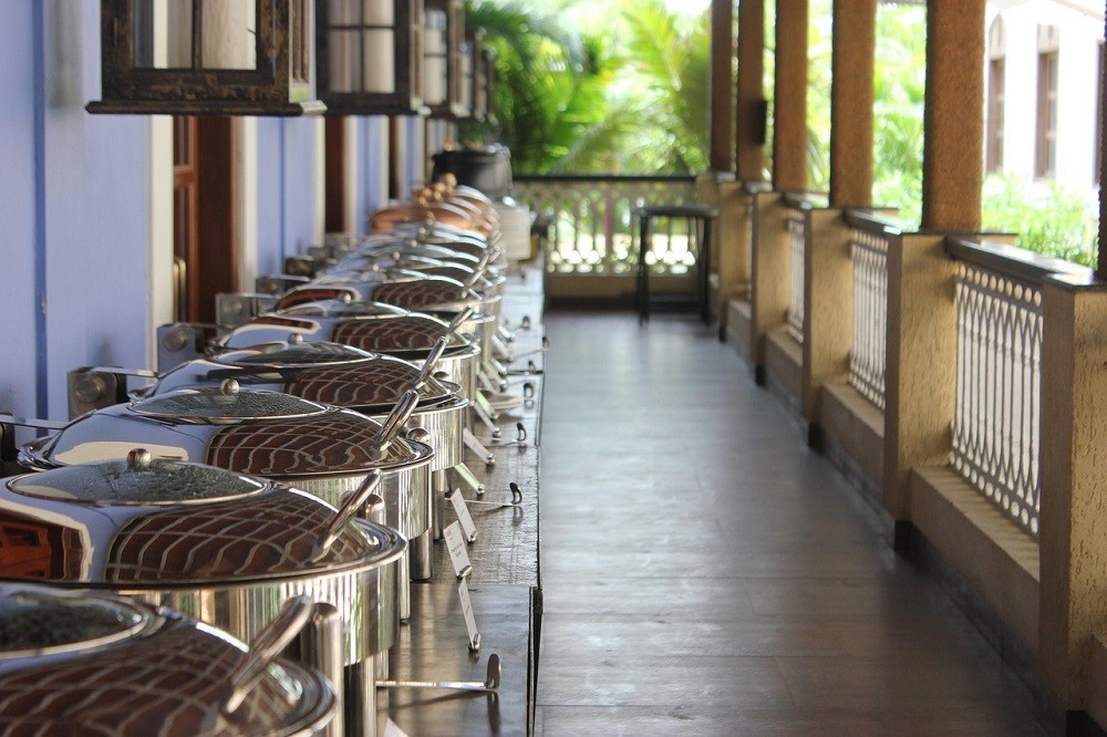 Several buffet-style serving containers are laid out on tables. They may be filled with food
