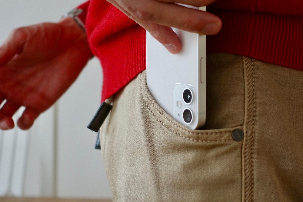 Someone is putting their white smartphone in their pocket