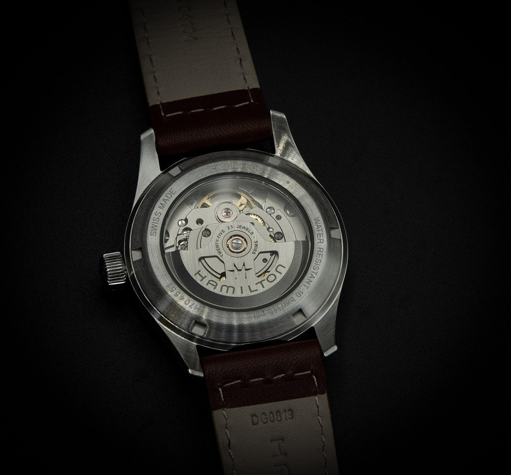 The exhibition caseback of a watch is shown. The movement and rotor are visible with the name 