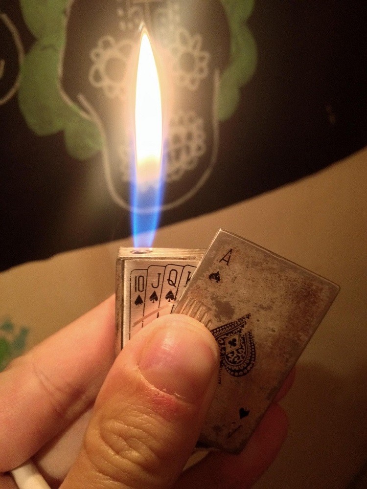 A soft flame lighter is in the shape of a deck of cards. The ace of spades is on the front of the lighter